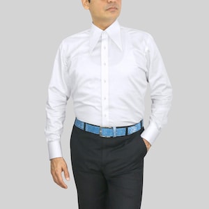 May include: A white dress shirt with a wide collar and long sleeves. The shirt is paired with black pants and a light blue belt with a snakeskin pattern. The belt has a silver-colored buckle.