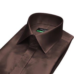 May include: A folded, dark brown dress shirt with a pointed collar and two buttons. The shirt has a satin-like sheen and a label that reads "John Cloth London". The shirt is neatly folded.