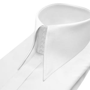 Può includere: Tazza in ceramica bianca con manico nero e la scritta "But First, Coffee" in nero. La tazza è posta su uno sfondo sfocato, suggerendo un'atmosfera accogliente.