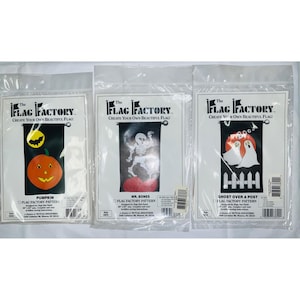 May include: Three Halloween-themed flag patterns in plastic packaging. The patterns include a pumpkin with a bat, a skeleton, and two ghosts over a fence. Each package features the text "The Flag Factory" and "Create Your Own Beautiful Flag!"