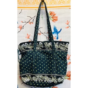 Bolso tote acolchado azul marino con estampado floral, cierre de botón, asas largas y bolsillos. Medidas: 17x14.