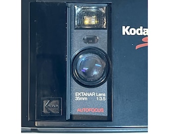 Cámara de película Kodak Serie S de 35 mm de los años 80 con lente Ektanar, enfoque automático y flash, con estuche.