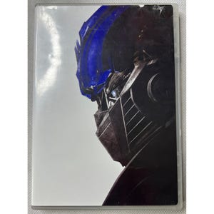 Op de afbeelding: DVD-hoes met een close-up van het gezicht van een robot, met blauwe en metallic grijze details. Het oog van de robot is zichtbaar, tegen een witte achtergrond. De hoes zit in een doorzichtige plastic hoes.