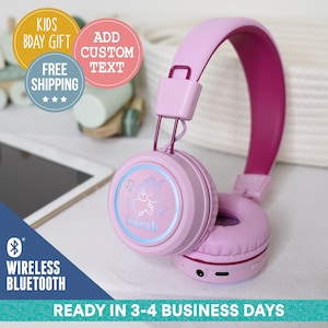 Könnte beinhalten: Rosa drahtlose Bluetooth-Kopfhörer mit einem Einhorn-Design und einer Leuchtfunktion. Die Kopfhörer haben ein rosa Kopfband und Ohrmuscheln mit einem violetten Akzent am Kopfband. Die Ohrmuscheln haben einen hellblauen Schein um das Einhorn-Design.