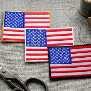 May include: Three rectangular embroidered patches featuring the United States flag design with red, white, and blue thread. Each patch displays a blue canton with white stars and horizontal red and white stripes, finished with distinct border stitching.