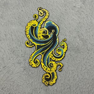 May include: A blue and yellow embroidered octopus patch. The octopus has eight tentacles and is curled up in a spiral shape.