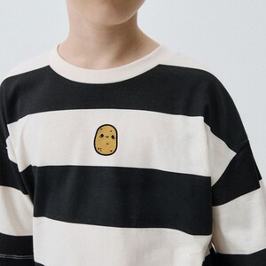 Op de afbeelding: Zwart-wit gestreept T-shirt met een schattige aardappelafbeelding. De top met korte mouwen heeft een ronde hals en een losse pasvorm. De aardappelafbeelding is op de voorkant geborduurd.