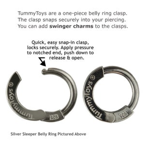 Puede incluir: Dos cierres de anillo de vientre de plata con las palabras "Tummy Toys" grabadas en ellos. Los cierres est&aacute;n abiertos y muestran el mecanismo para sujetar a un piercing.