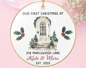 May include: Round Christmas ornament with a gold rim and a gold string for hanging. The ornament features a watercolor illustration of a white door with a wreath, holly, and the text "OUR FIRST CHRISTMAS AT" and "248 MAPLEWOOD LANE Kate & Marc EST. 2025."