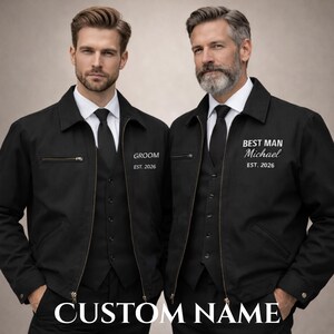 May include: Two black jackets with the text "GROOM EST. 2026" and "BEST MAN Michael EST. 2026". The jackets have a zip closure, a collar, and are worn over a black waistcoat and tie. The bottom of the image reads "CUSTOM NAME".