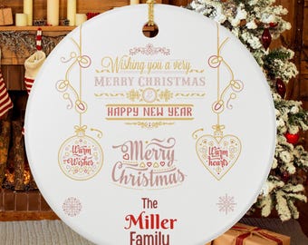 May include: A white Christmas ornament with gold and pink text. The ornament says "Wishing you a very Merry Christmas Happy New Year" and "Merry Christmas". It also says "Warm Wishes" and "Warm Hearts". The Miller Family is also printed on the ornament.