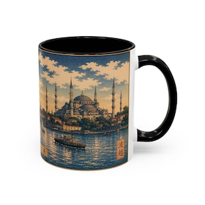 Peut inclure: Un mug en céramique avec une anse et un intérieur noirs, orné d'une illustration panoramique d'une mosquée avec plusieurs minarets et un dôme central au bord de l'eau avec un bateau, sous un ciel bleu nuageux et des caractères japonais.