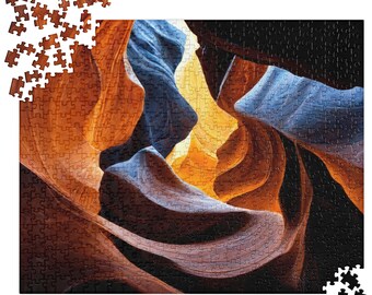 Könnte beinhalten: Ein fertiges Puzzle mit einem Canyon mit orangefarbenen, braunen und blauen Felsformationen. Einige Puzzleteile sind um das fertige Puzzle herum verstreut. Ein entspannendes Hobby für alle Altersgruppen.