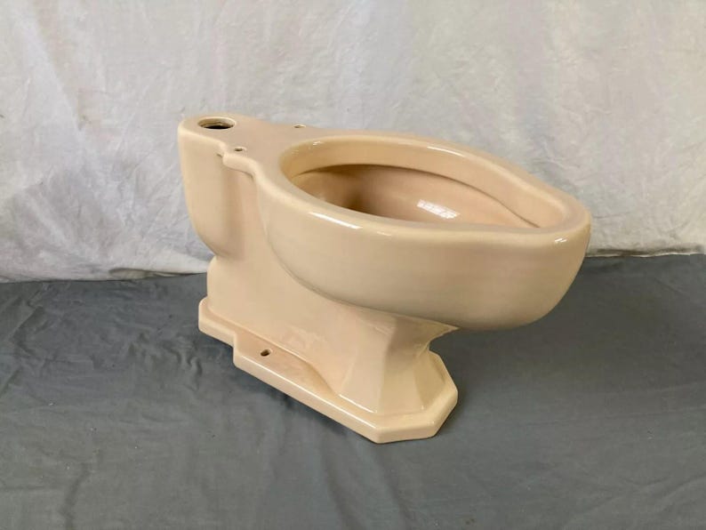 May include: A vintage, off-white toilet bowl with a rounded bowl and a pedestal base. The toilet is made of ceramic and has a smooth, glossy finish.