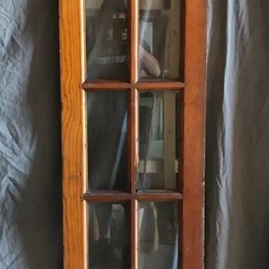 May include: A vintage wooden door with a single pane of glass divided into nine smaller panes. The door is painted a light brown color and has a brass handle.