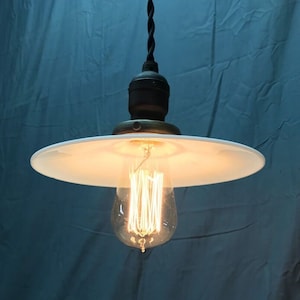 May include: A white porcelain pendant light fixture with a clear glass bulb and a black cord.