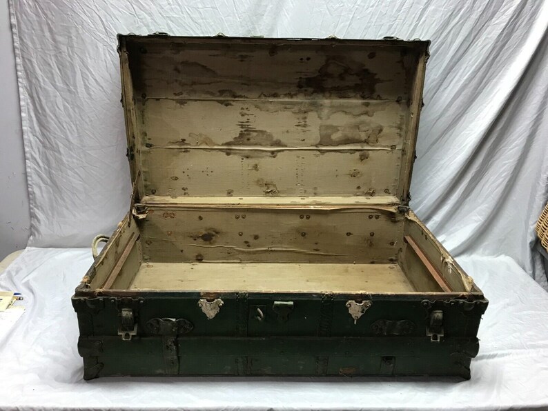 May include: A vintage green wooden trunk with metal hardware and a worn interior. The trunk is open and empty, revealing the wooden interior.