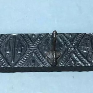 May include: Black metal coat rack with three hooks and a decorative patterned design.