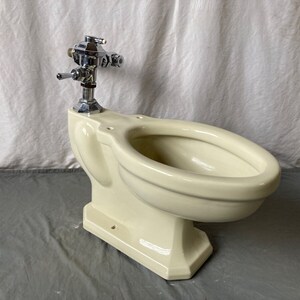 K&ouml;nnte beinhalten: Eine vintage Toilette in cremewei&szlig; mit einem verchromten Sp&uuml;lventil.