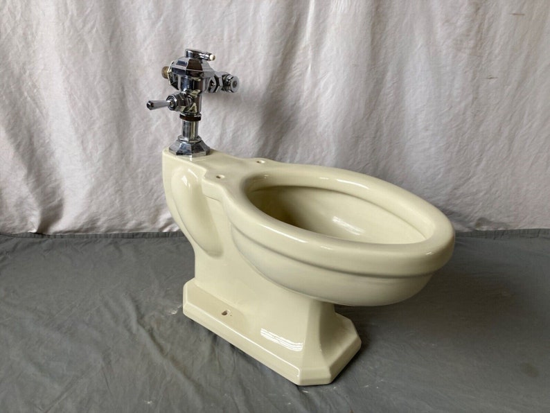 K&ouml;nnte beinhalten: Eine vintage Toilette in cremewei&szlig; mit einem verchromten Sp&uuml;lventil.