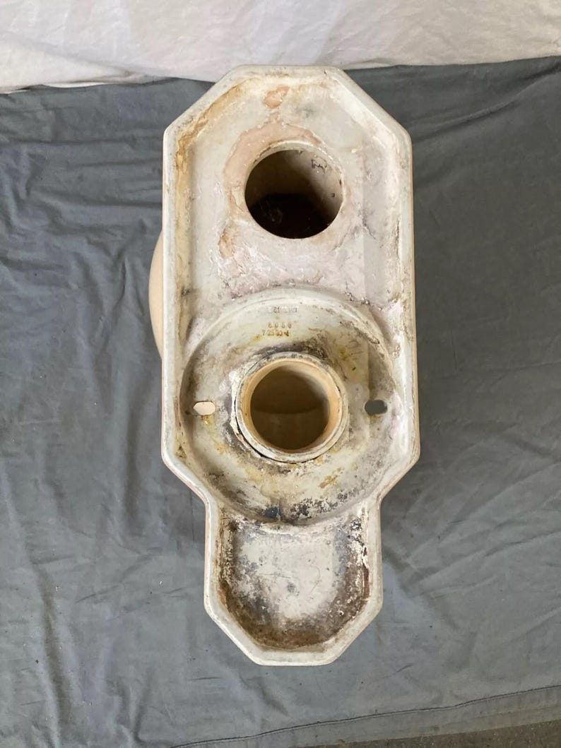 May include: White ceramic toilet bowl base with a round opening and a smaller round opening on the top. The base has a decorative design with a scalloped edge. The base is marked with the text "4444 70000".