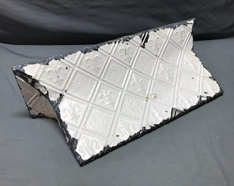 May include: A white ceramic tile with a diamond pattern and a black border. The tile is slightly chipped and worn, giving it a vintage look.