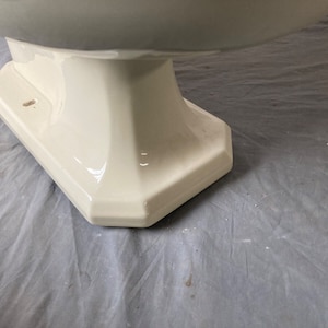 K&ouml;nnte beinhalten: Nahaufnahme der Basis einer wei&szlig;en Porzellan-Toiletten-Sch&uuml;ssel. Die Basis ist ein Sockel mit einer glatten, gl&auml;nzenden Oberfl&auml;che.