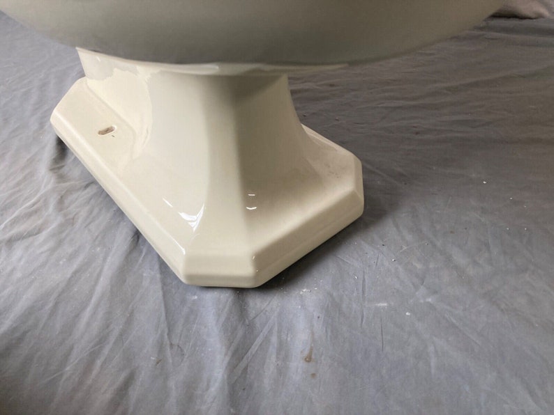 K&ouml;nnte beinhalten: Nahaufnahme der Basis einer wei&szlig;en Porzellan-Toiletten-Sch&uuml;ssel. Die Basis ist ein Sockel mit einer glatten, gl&auml;nzenden Oberfl&auml;che.