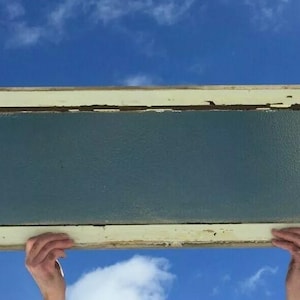 May include: A vintage, white-painted window frame with a frosted glass pane. The frame has a distressed look with some chipped paint and visible wood grain.