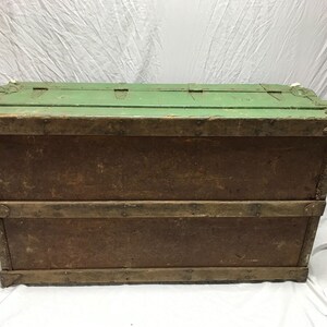 May include: A vintage wooden storage trunk with a green painted top and brown wood sides. The trunk has metal hinges and clasps.