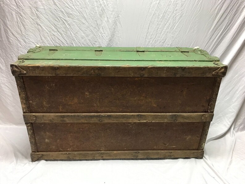 May include: A vintage wooden storage trunk with a green painted top and brown wood sides. The trunk has metal hinges and clasps.