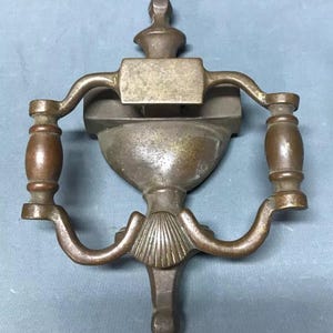 May include: Antique brass door knocker with a decorative shell design and two ornate handles.