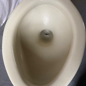K&ouml;nnte beinhalten: Eine wei&szlig;e Toiletten-Sch&uuml;ssel aus Keramik mit glatter, gl&auml;nzender Oberfl&auml;che. Die Sch&uuml;ssel ist oval geformt und hat eine gro&szlig;e &Ouml;ffnung oben.