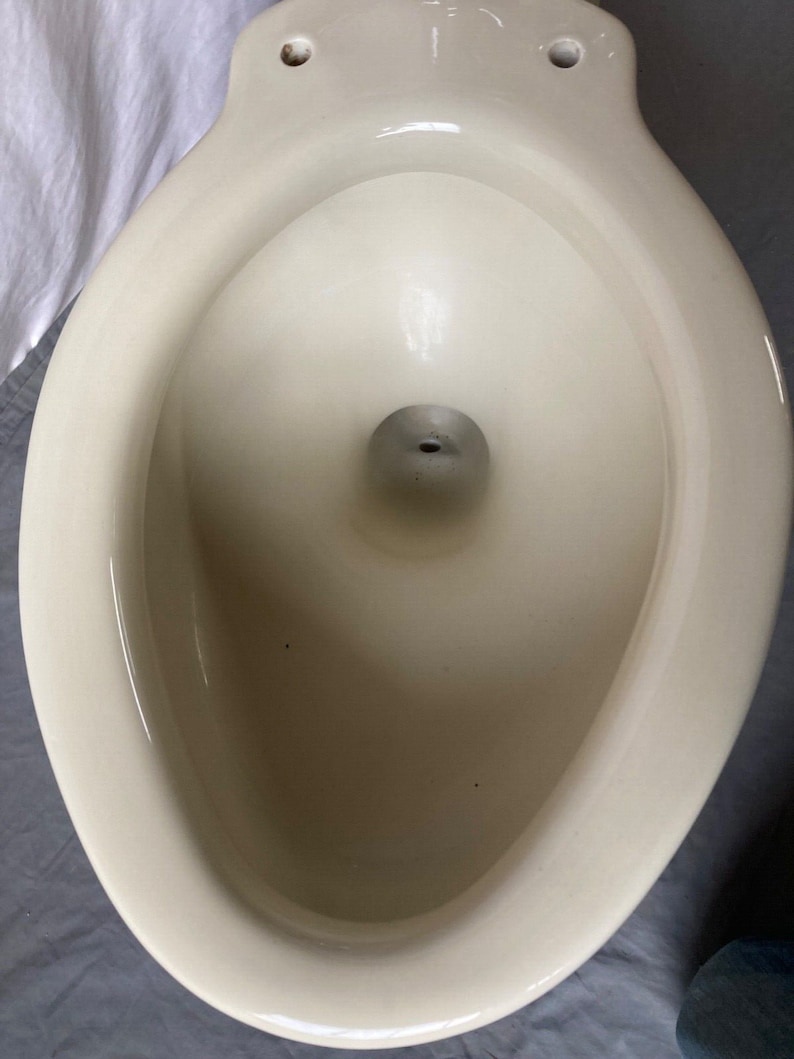 K&ouml;nnte beinhalten: Eine wei&szlig;e Toiletten-Sch&uuml;ssel aus Keramik mit glatter, gl&auml;nzender Oberfl&auml;che. Die Sch&uuml;ssel ist oval geformt und hat eine gro&szlig;e &Ouml;ffnung oben.