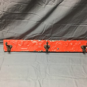 May include: A red metal hook rack with three hooks. The rack has a decorative embossed pattern.