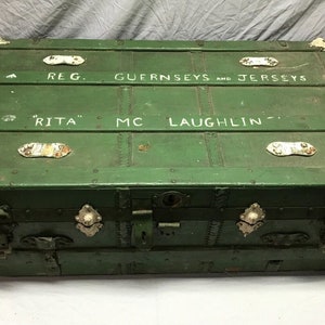 May include: A vintage green wooden trunk with metal hardware and white painted lettering that reads "REG. GUERNSEYS AND JERSEYS "RITA" MC LAUGHLIN -"