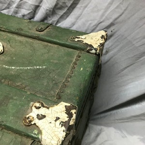 May include: Green wooden storage trunk with metal hardware and white paint accents. The trunk has a distressed look with chipped paint and visible wood grain.