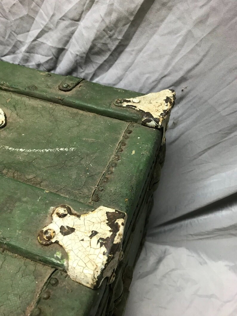 May include: Green wooden storage trunk with metal hardware and white paint accents. The trunk has a distressed look with chipped paint and visible wood grain.