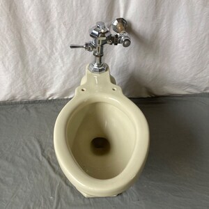 K&ouml;nnte beinhalten: Eine vintage Toilette in off-wei&szlig; mit einem verchromten Sp&uuml;lventil und einem Holzgriff.