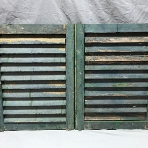 May include: A pair of weathered green wooden shutters with a metal latch. The shutters are closed and have a distressed look.
