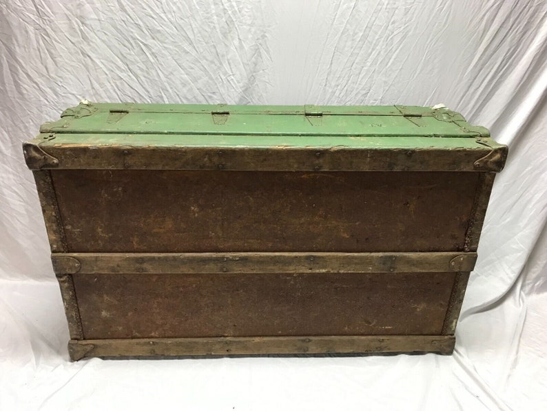 May include: A vintage wooden storage trunk with a green painted top and brown wood sides. The trunk has metal hinges and clasps.