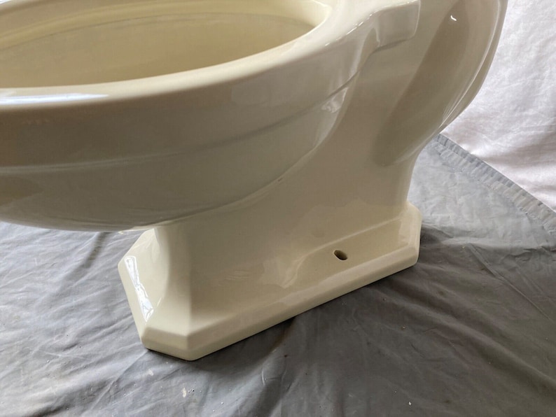 May include: A cream-colored toilet bowl with a rounded, oval-shaped bowl and a pedestal base. The toilet bowl is made of ceramic and has a smooth, glossy finish.