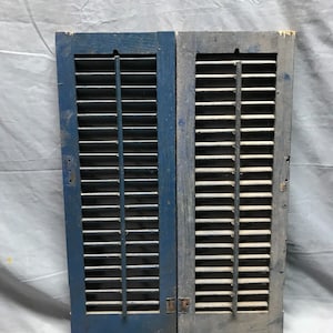 May include: A pair of antique wooden shutters, one painted blue and the other with natural wood finish. Both shutters have multiple louvers and are in good condition.