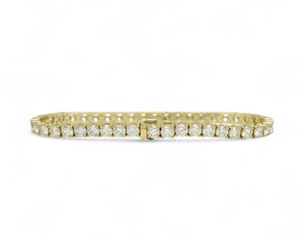 Puede incluir: Un brazalete de tenis de oro con una fila de diamantes redondos.