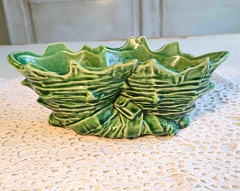 May include: A green ceramic decorative bowl with a leaf-like design. The bowl has a textured surface and a glossy finish. The bowl is a vibrant shade of green and is likely used for decorative purposes.