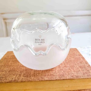 May include: A clear glass bowl with a frosted white interior and a wavy rim. The bowl has the text "HOLME GAARD 1825" printed on the side.