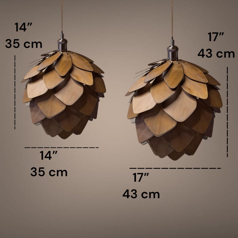 Puede incluir: Dos l&aacute;mparas colgantes de madera, con forma de pi&ntilde;a, cuelgan del techo. Est&aacute;n hechas de paneles de madera en capas en tonos marrones. Una mide 35 cm de ancho, la otra 43 cm.