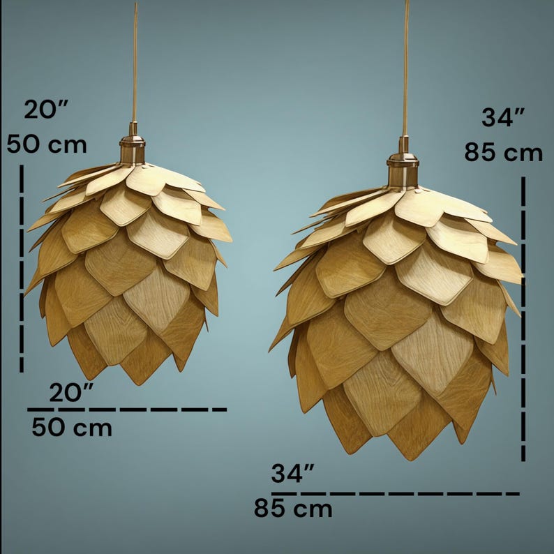 Puede incluir: Dos l&aacute;mparas colgantes de madera, una de 50 cm de ancho y la otra de 85 cm. Cada l&aacute;mpara tiene un dise&ntilde;o en capas, en forma de p&eacute;talos, en tonos marr&oacute;n claro y est&aacute; suspendida por un fino cable dorado.