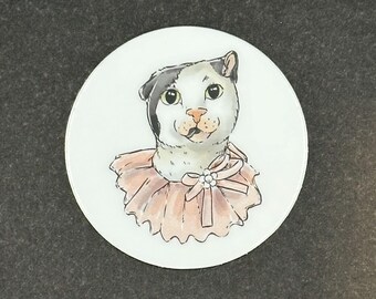 Könnte beinhalten: Ein weißer Keramikteller mit einer handgemalten Illustration einer schwarz-weißen Katze, die ein rosa Rüschenkragen mit einer weißen Schleife trägt.