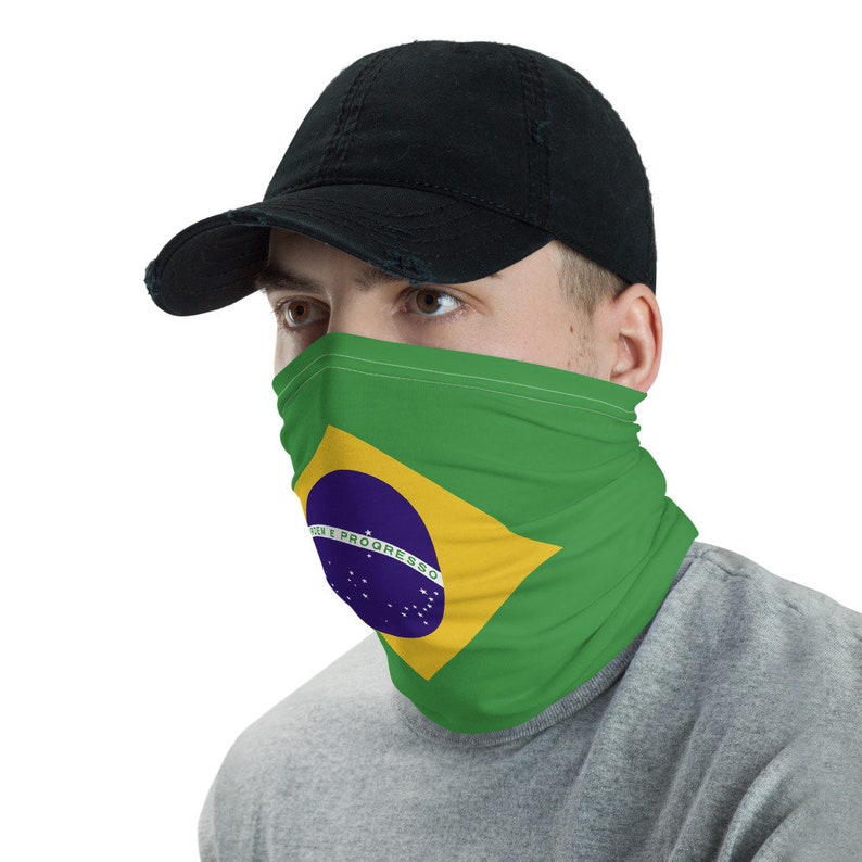 Pu&ograve; includere: Una persona indossa un cappello da baseball nero e una copertura per il viso con la bandiera brasiliana stampata su di essa. La bandiera &egrave; verde, gialla, blu e bianca con un cerchio al centro che dice "Ordem e Progresso".